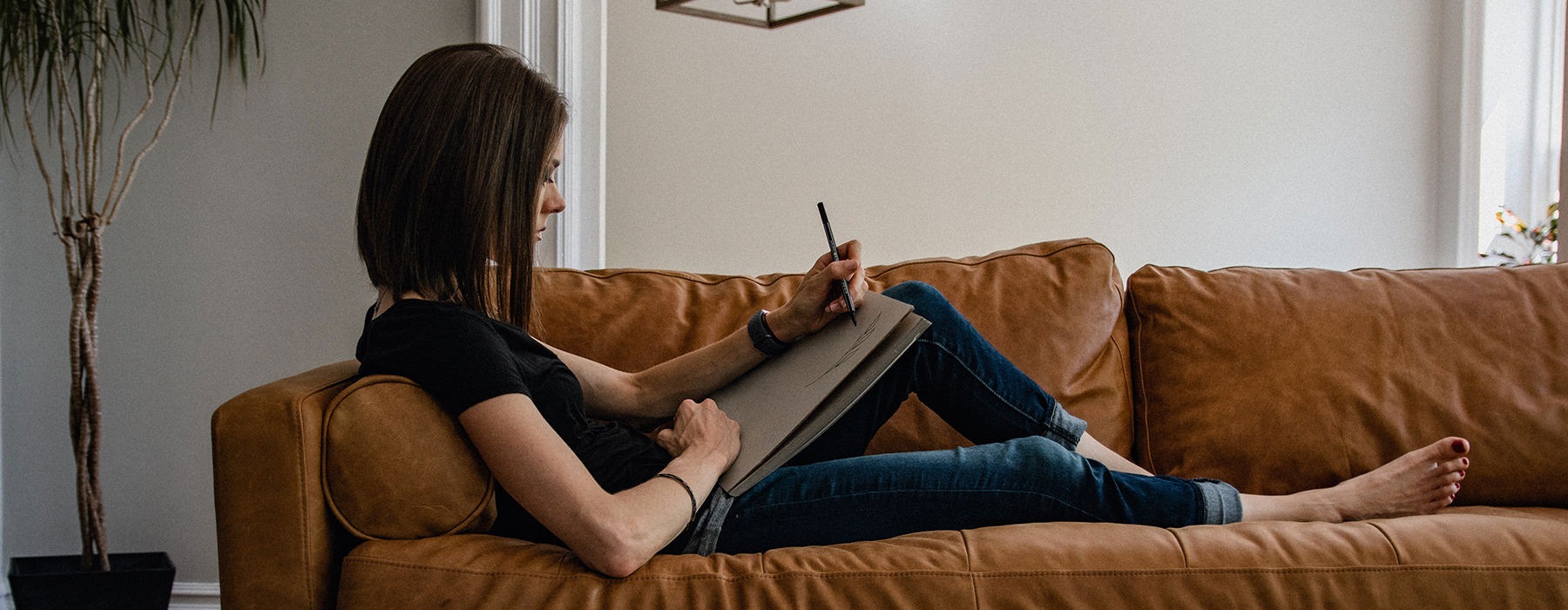 Woman relaxing on her couch writing 
