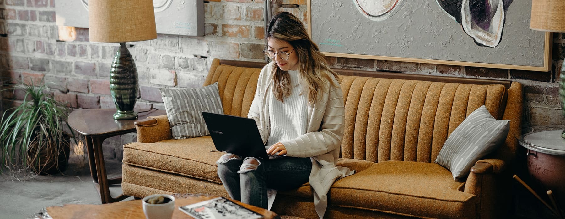 lifestyle image of a woman sitting on a couch working on her laptop